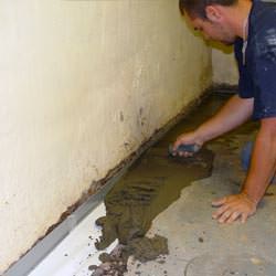 A basement waterproofer installing a perimeter drain system in Spearman