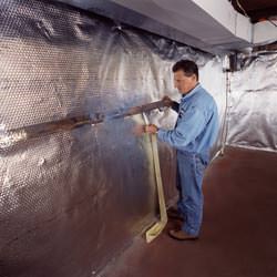 Installation of a radiant heat and vapor barrier on a basement wall in Clarendon