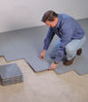 Contractors installing basement subfloor tiles and matting on a concrete basement floor in Plainview, Texas